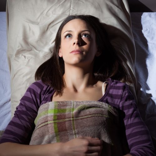 Vrouw die wakker ligt door het piekeren en last heeft van slapeloosheid